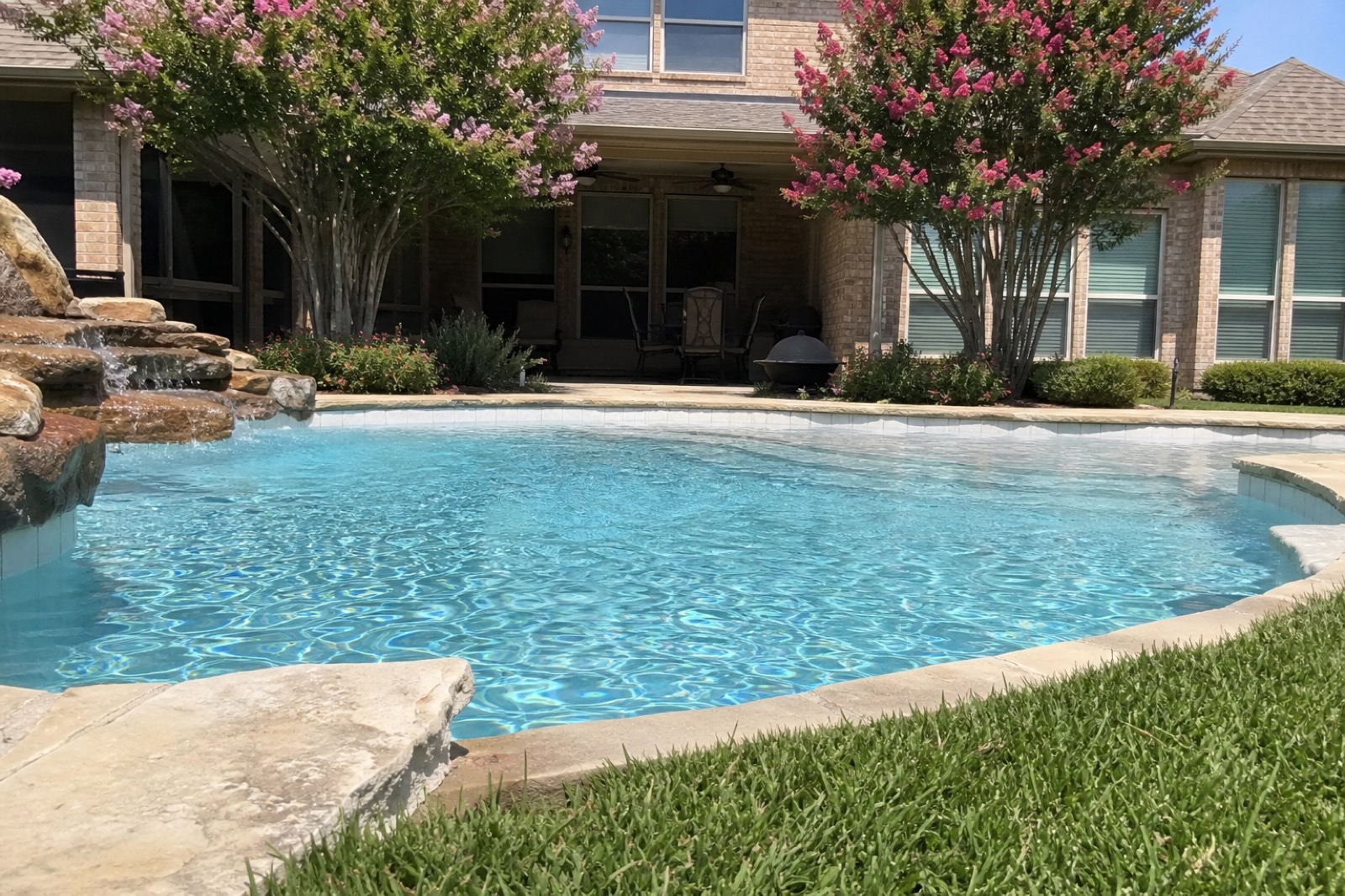 Crystal-clear backyard pool with brick patio and crepe myrtle trees, McKinney TX