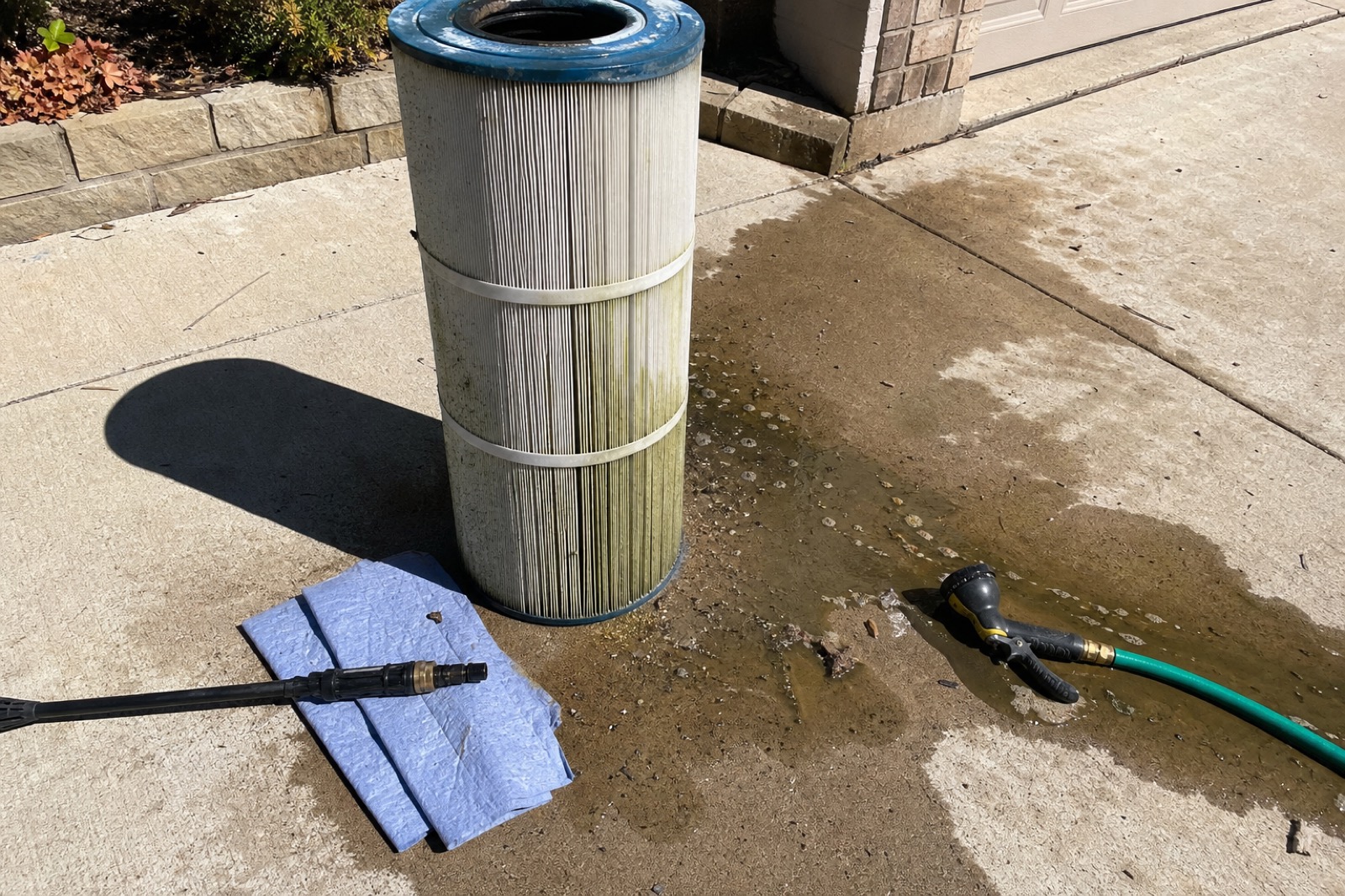 Used pool filter cartridge on driveway during cleaning